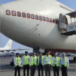 a group of men in reflective vests standing in front of an airplane